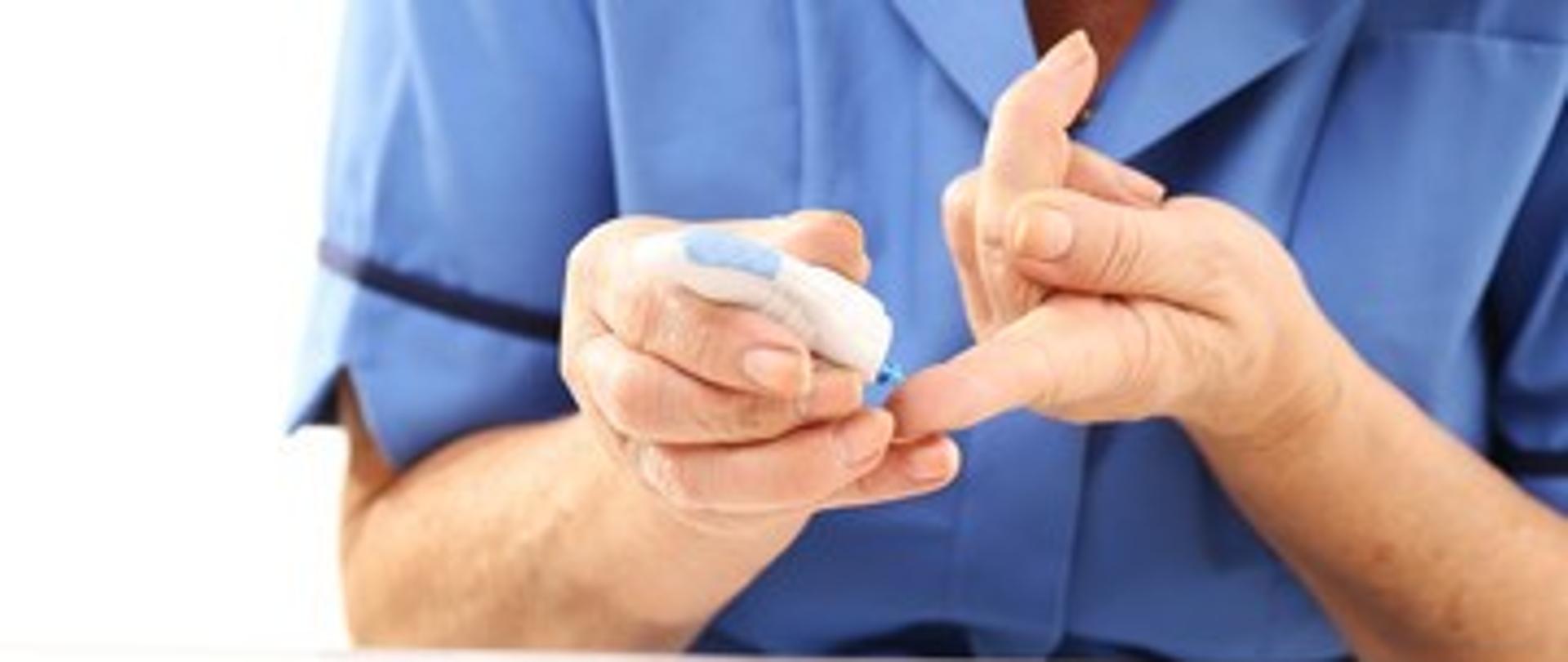 Człowiek dokonujący pomiaru cukru we krwi przy pomocy glukometru 