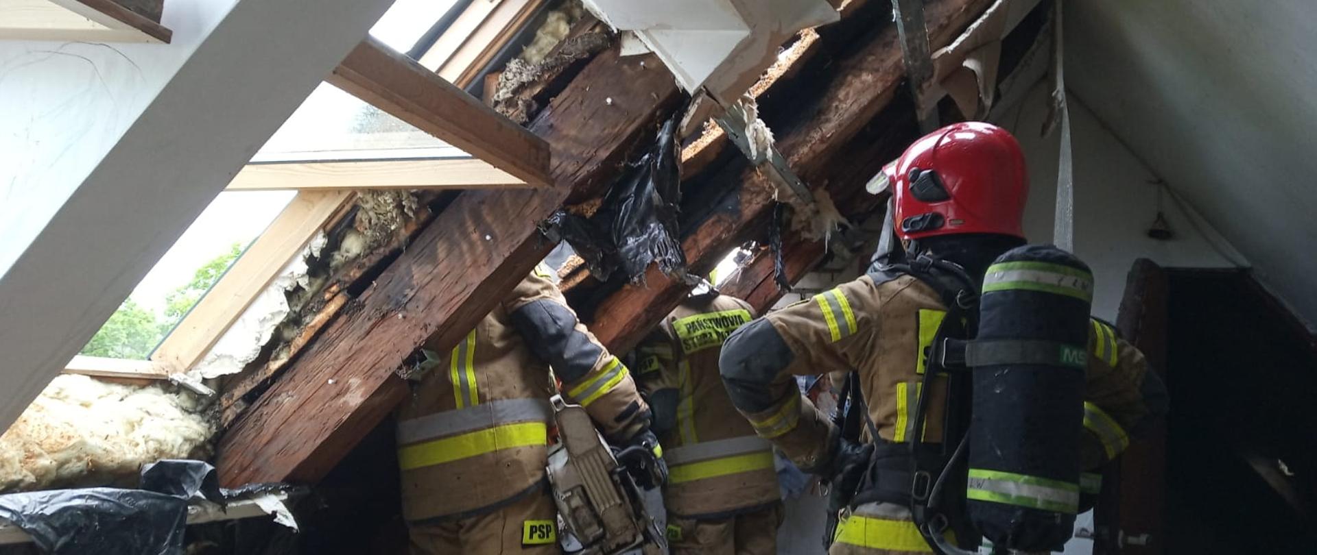 Zdjęcie przedstawia strażaków podczas działań związanych z usuwaniem elementów wyposażenia poddasza