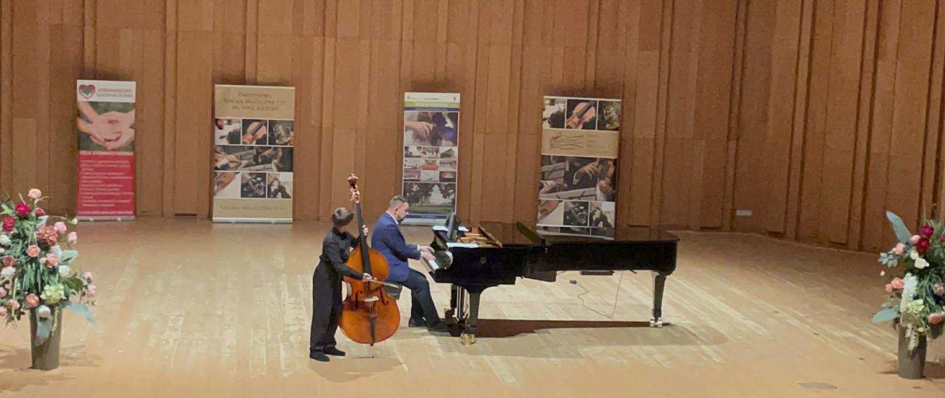 Uczeń grający na kontrabasie z akompaniamentem fortepianu podczas występu na scenie w trakcie I Ogólnopolskiego Konkursu Kontrabasowego w Sosnowcu.