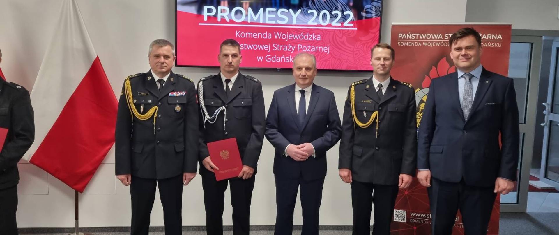 W pomieszczeniu Komendy Wojewódzkiej Państwowej Straży Pożarnej w Gdańsku stoją od lewej Pomorski Komendant Wojewódzki st. bryg. Piotr Socha, druh Sylwester Krawiec, wojewoda pomorski Dariusz Drelich, komendant powiatowy Państwowej Straży Pożarnej w Człuchowie Ernest Szczepański, prezes wojewódzkiego funduszu ochrony środowiska Szymon Gajda.