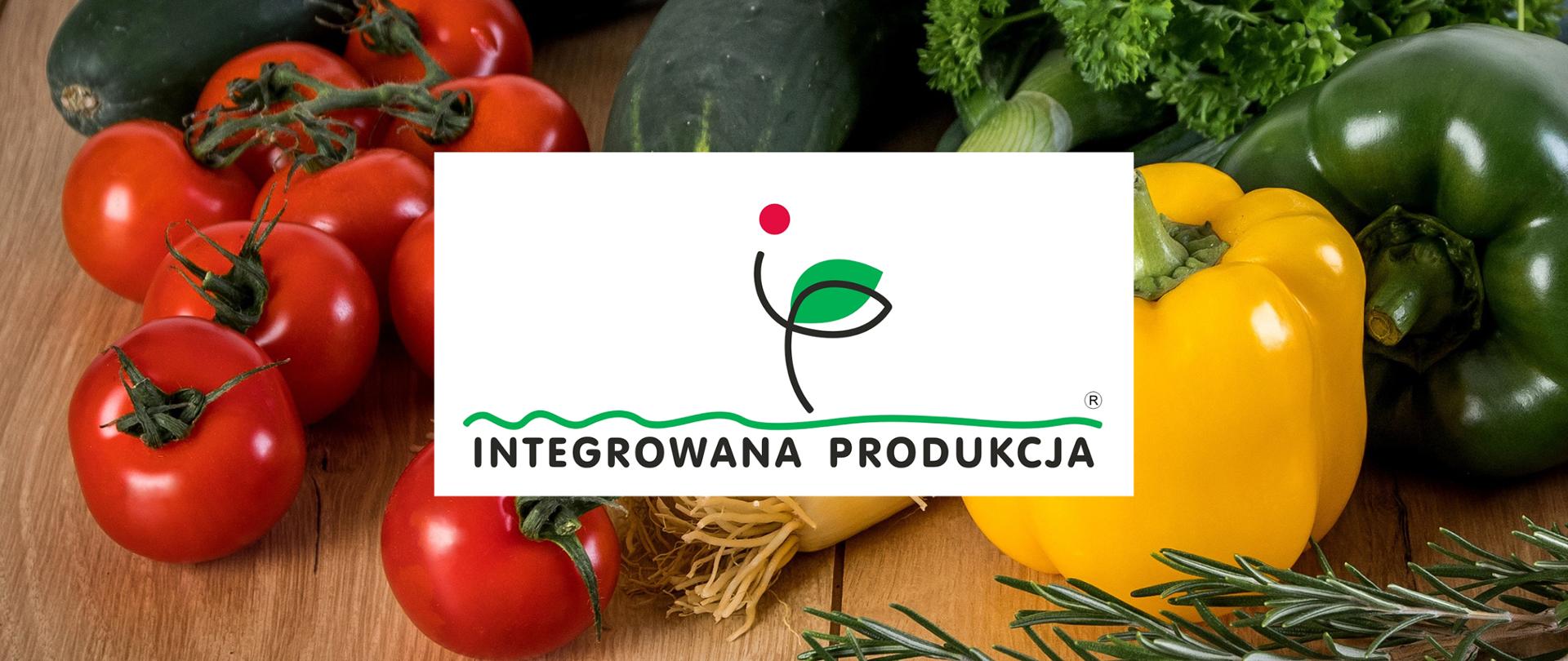 Logo Integrowana Produkcja na tle zdjęcia z warzywami: czerwonymi pomidorami, żółtą i zieloną papryką, ogórkami