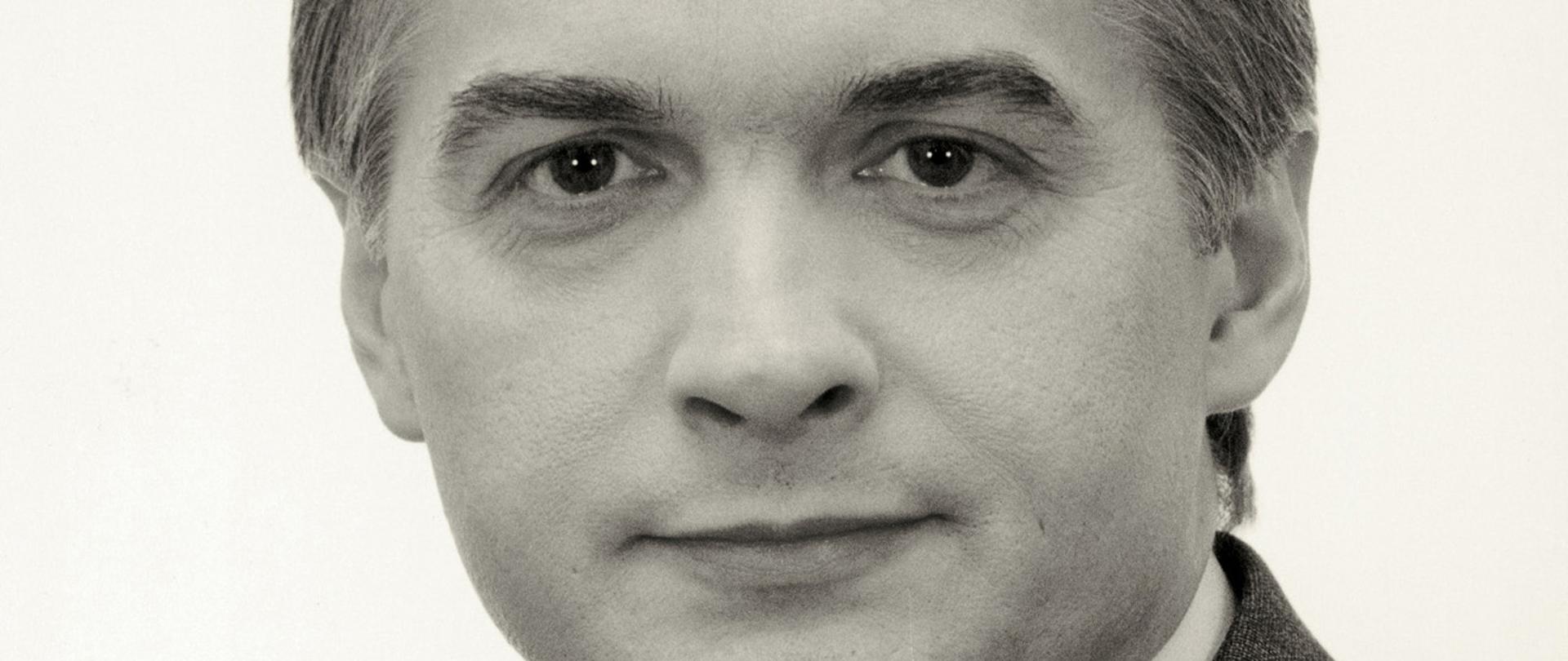 Włodzimierz Cimoszewicz czarno - biały portret mężczyzny, siwiejące włosy, szara marynarka w paski, wzorzysty krawat, biała koszula.