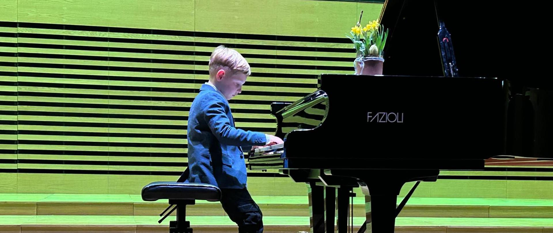Chłopczyk gra na fortepianie.