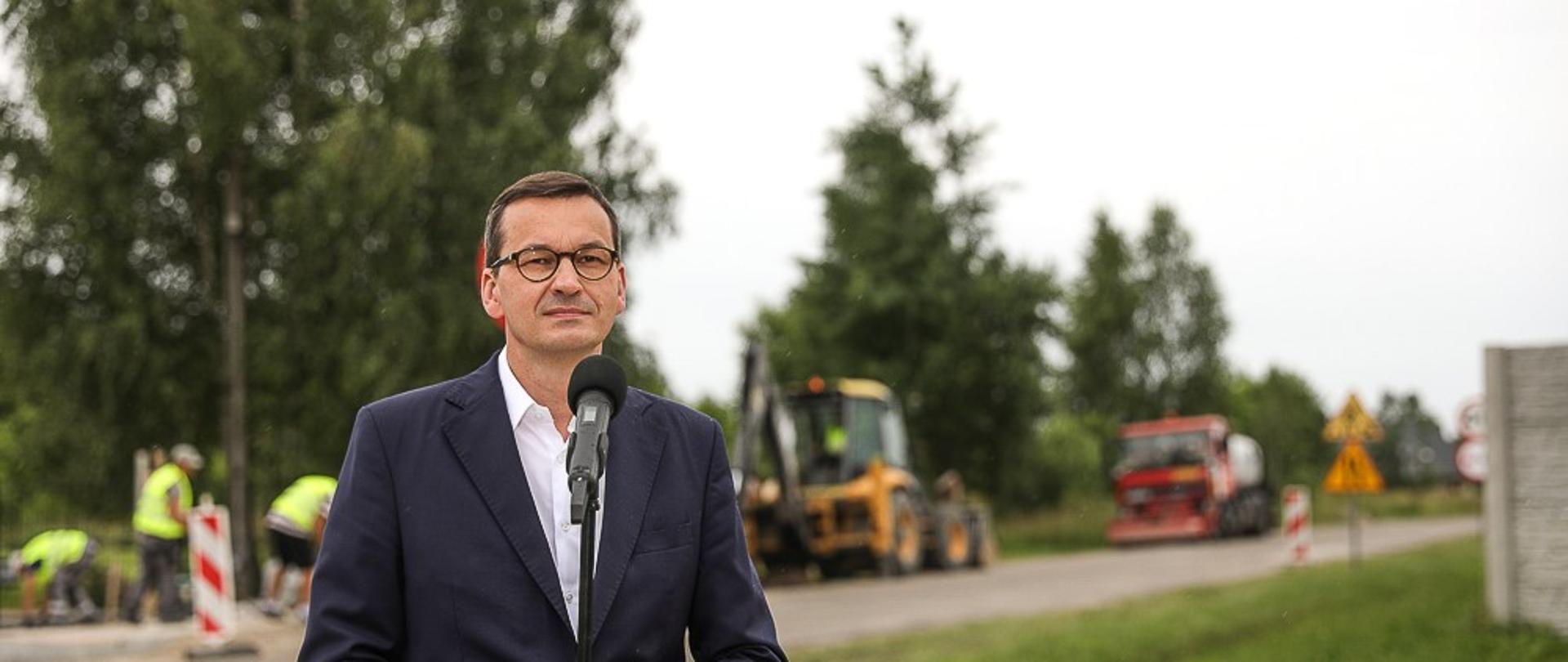 Przemówienie premiera na tle drogi.