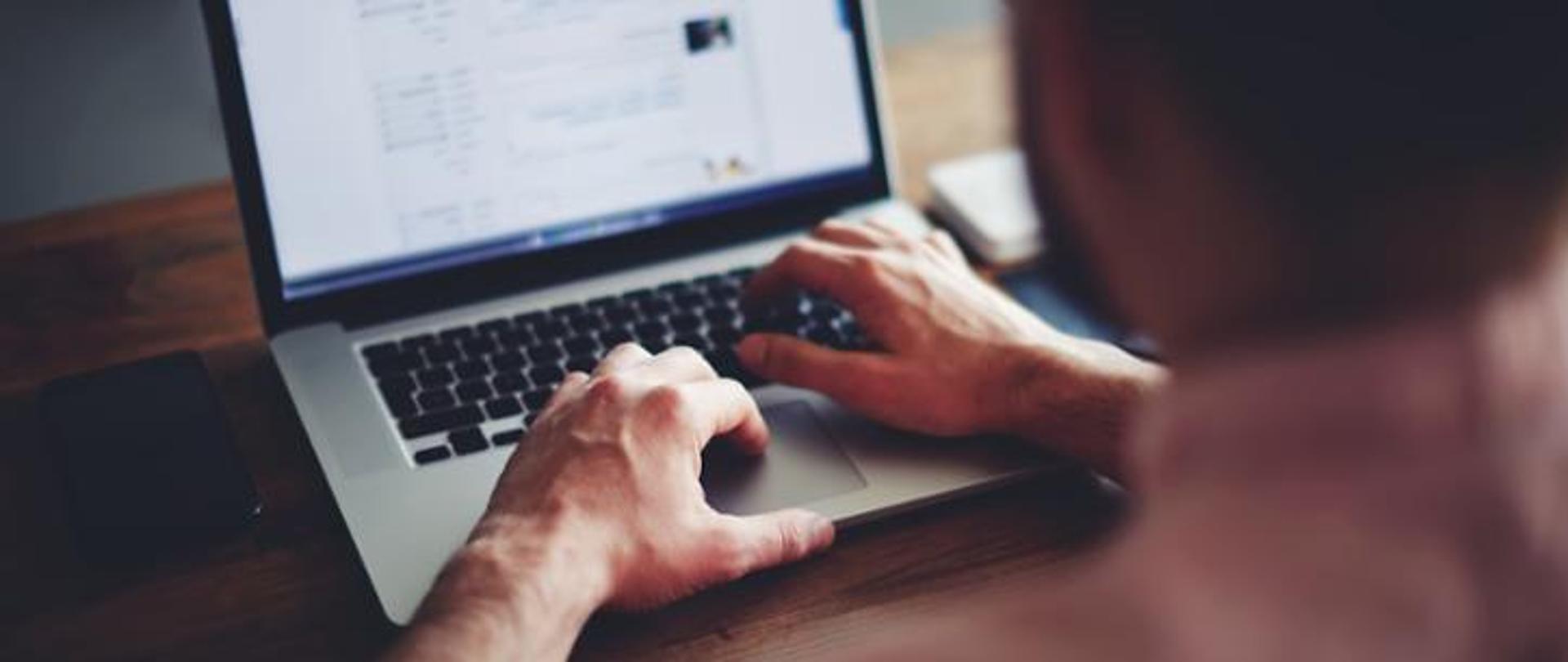 Osoba pracująca przy biurku na laptopie