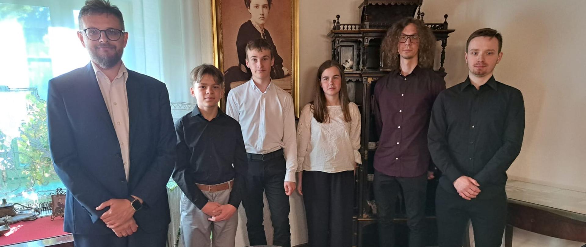 Wykonawcy stoją w sali Muzeum w Gosławicach