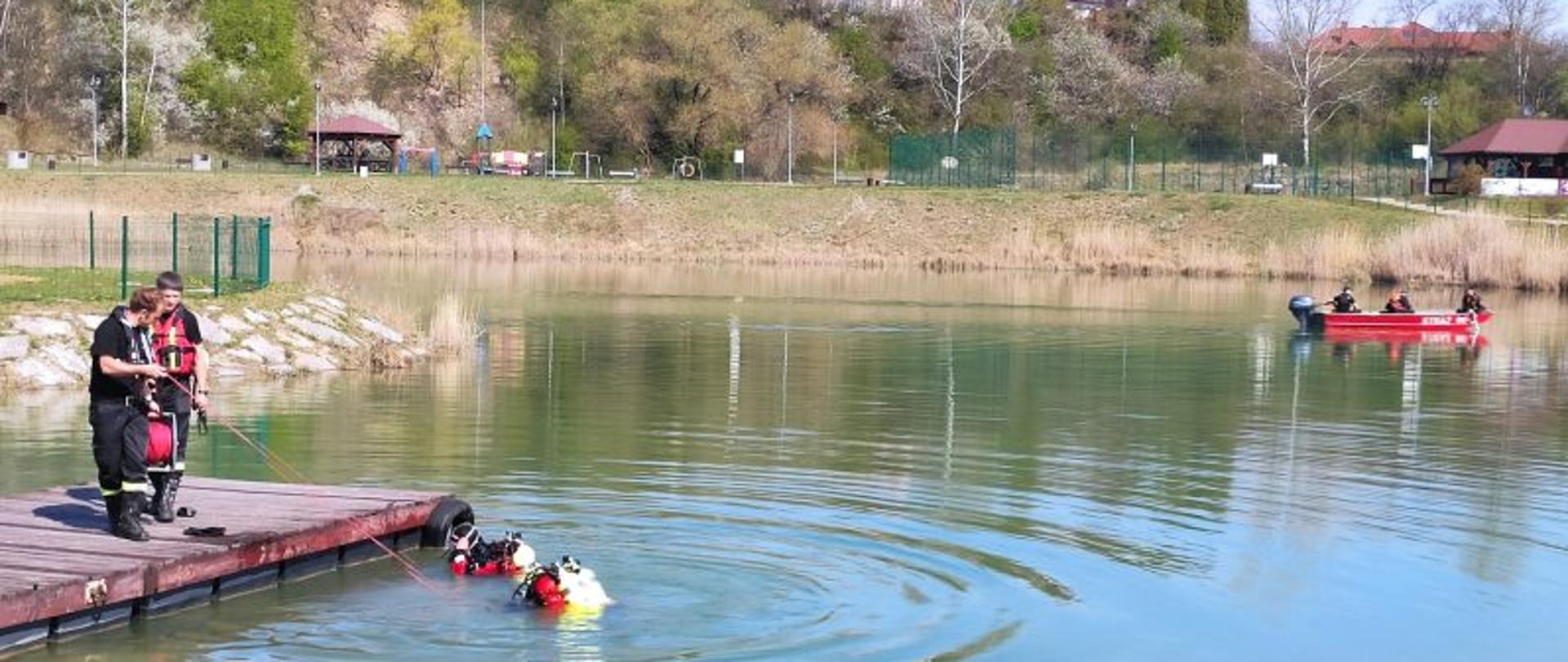 Staw przy ulicy Kwiatowej w Jaśle. We wodzie Strażacy Z JRG Jasło w poszukiwaniu mężczyzny który zaginął. Ogniomistrz Gierlicki Łukasz wprowadza na lince strażaka, który za chwilę się zanurzy. Wszystkiemu przygląda się kapitan Wnęk Janusz dowodzący akcją. W oddali strażacy na łódce również poszukujący zaginionego 
