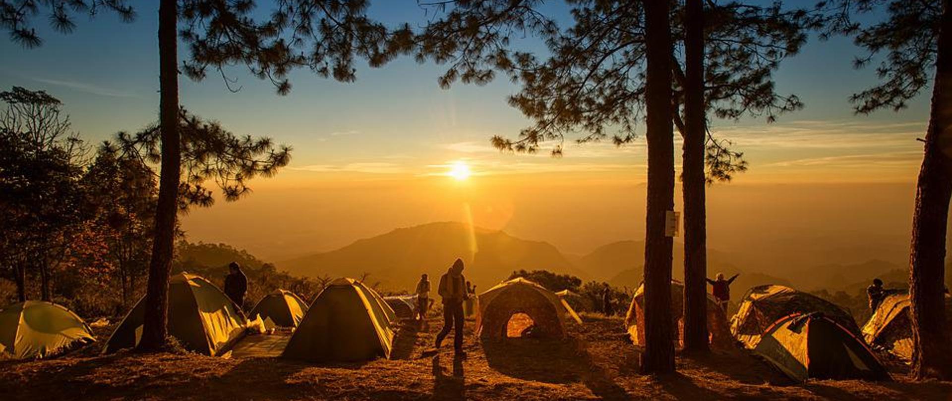 Obóz pod namiotami na tle zachodzącego słońca