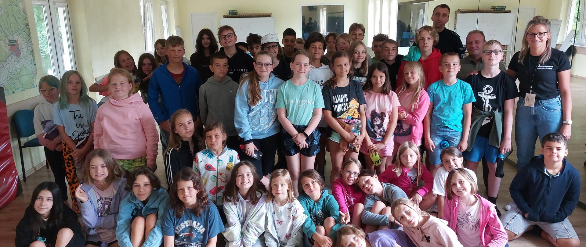 Zdjęcie grupowe, wykonane na obozie w Ośrodku "Szafir" w Moryniu. Na zdjęciu grupa ok. pięćdziesięciorga dzieci, policjant, leśnik i pracownik Inspekcji sanitarnej.