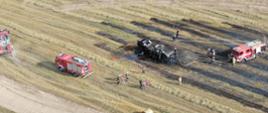 Ujęcie z drona. Spalony ciągnik i prasa do słomy. Strażacy gaszą maszyny rolnicze.