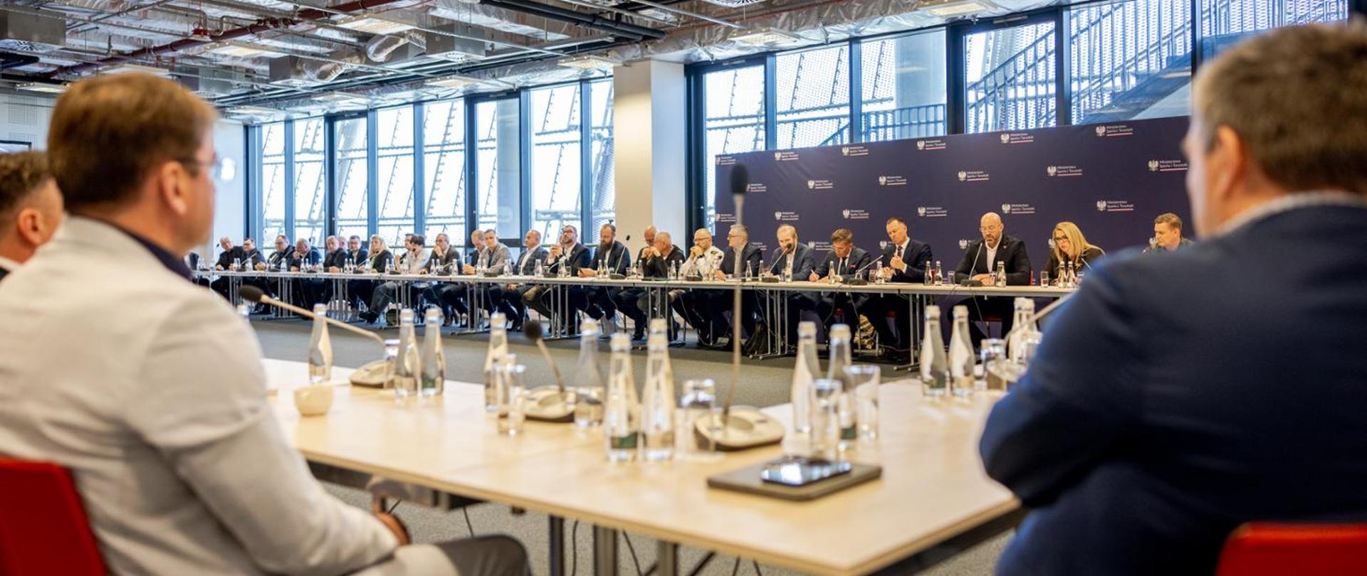 Representatives of Polish sports federations sit round a rectangular table. 