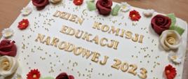 Tort ozdobiony kwiatami ze złotym napisem Dzień KEN 2023