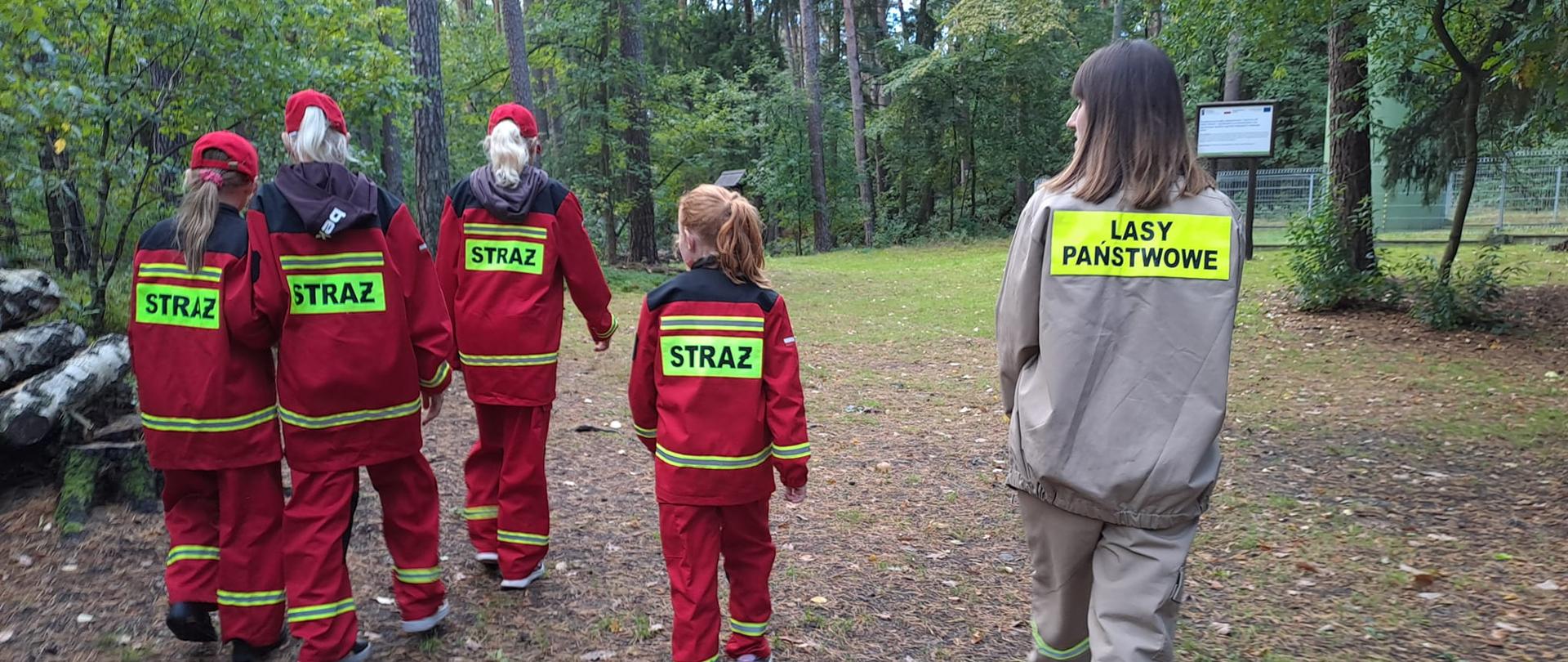 Dzieci z Młodzieżowej Drużyny Pożarniczej podczas szkolenia w lesie na temat oznaczenia oddziałów leśnych.