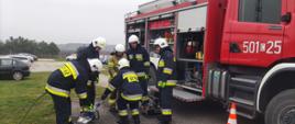 Zdjęcie przedstawia teren Komendy Powiatowej Państwowej Straży Pożarnej w Radziejowie oraz wóz strażacki, strażaków OSP podczas wykonywania ćwiczenia ze sprzętem hydraulicznym