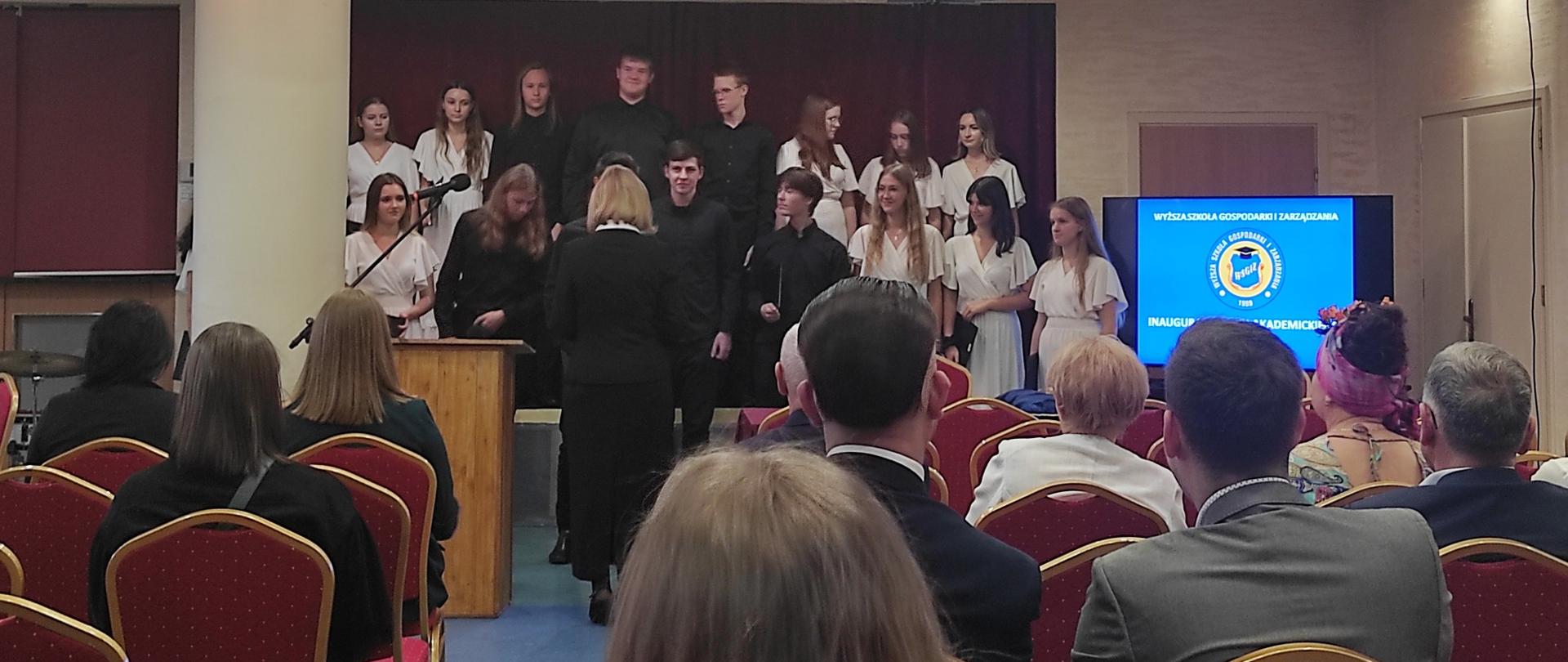 Chór PSM w Mielcu wraz z dyrygentką Renatą Wrażeń podczas występu w audytorium Wyższej Szkole Gospodarki i Zarządzania w Mielcu z okazji inauguracji roku akademickiego 2023/2024