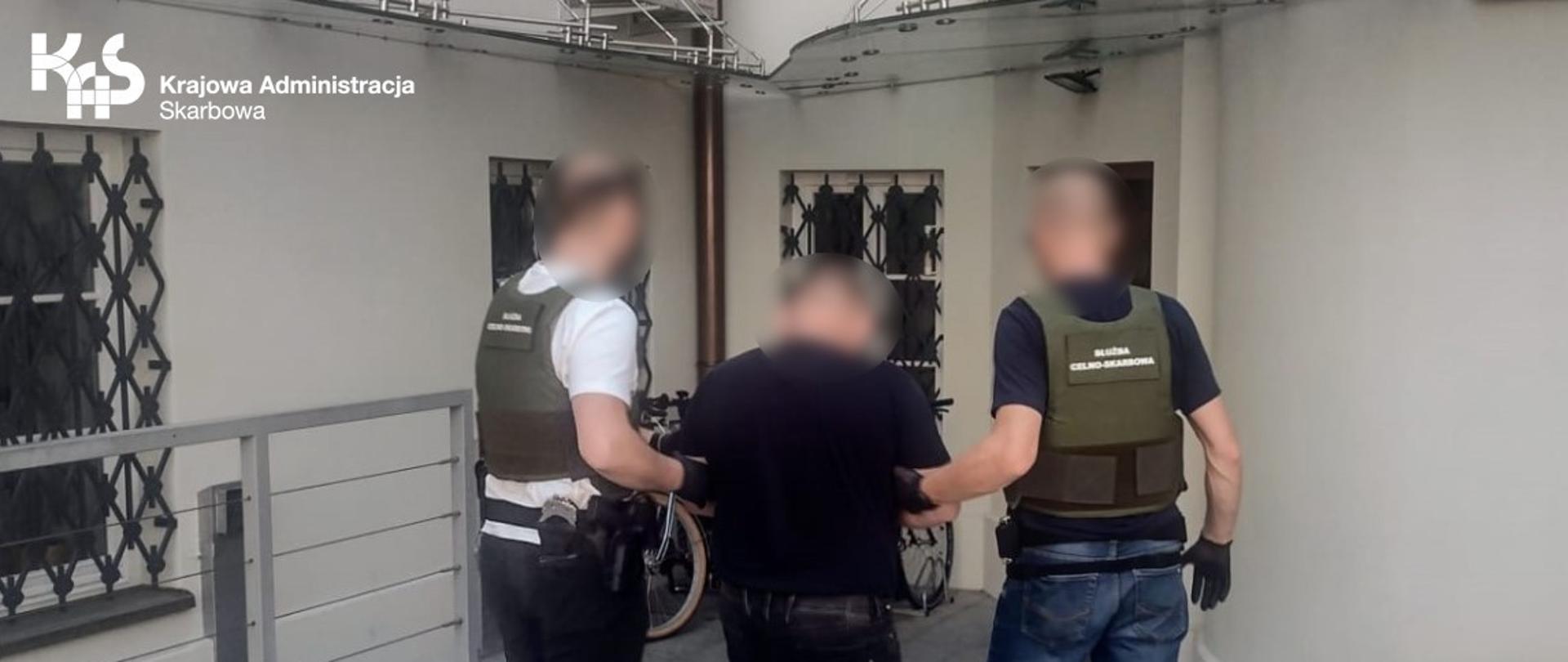 Funkcjonariusze KAS z zatrzymanym mężczyzną.