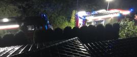 Na zdjęciu dwa samochody strażackie. Kadr zrobiony z dachu domu mieszkalnego w porze nocnej.