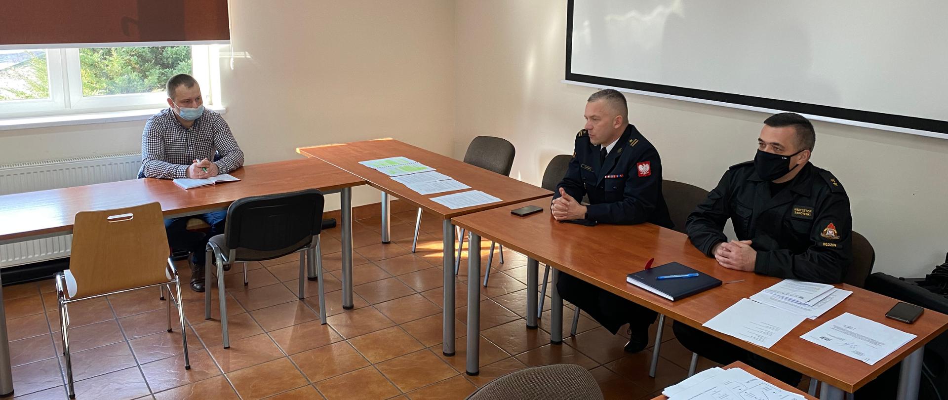 Na zdjęciu widzimy Komendanta Powiatowego PSP w Będzinie wraz z pracownikiem komendy podczas spotkania z przedstawicielami samorządów terytorialnych na sali sztabowej tut. komendy