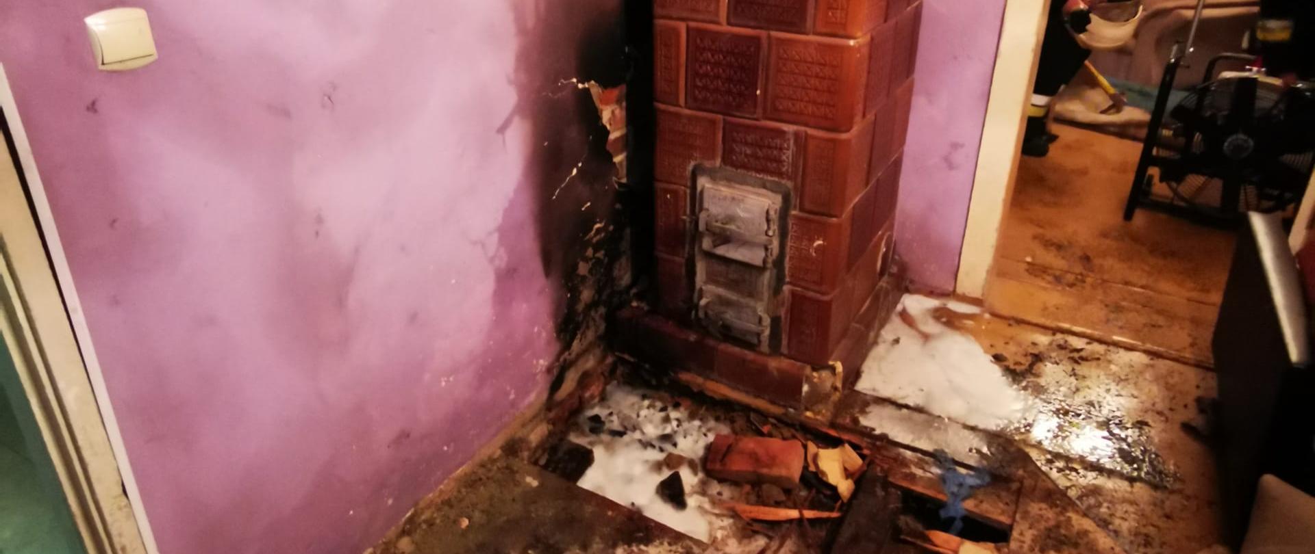 Zdjęcie przedstawia piec kaflowy oraz skutki pożaru w mieszkaniu