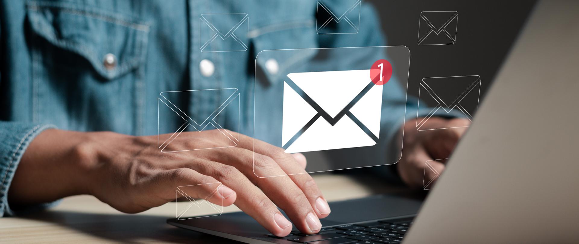 Osoba siedząca przed komputerem, widoczny symbol koperty z liczbą 1