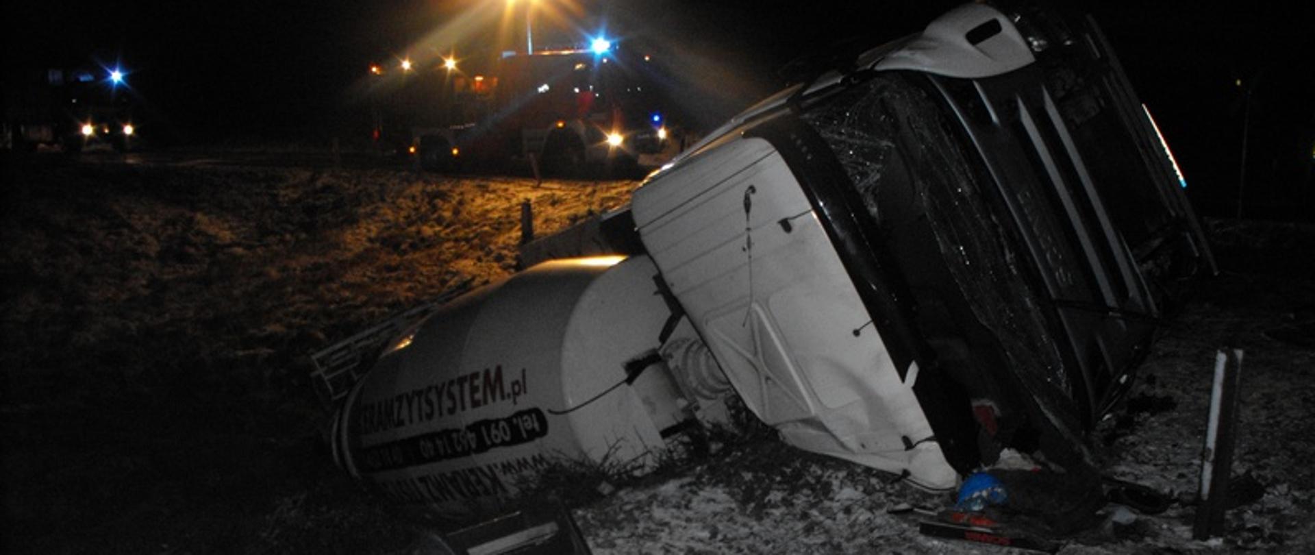 Zdjęcie przedstawia przewrócony samochód ciężarowy
