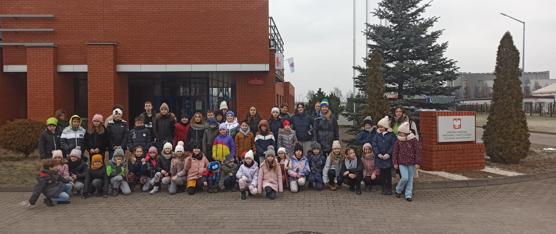 Grupa dzieci przed budynkiem komendy