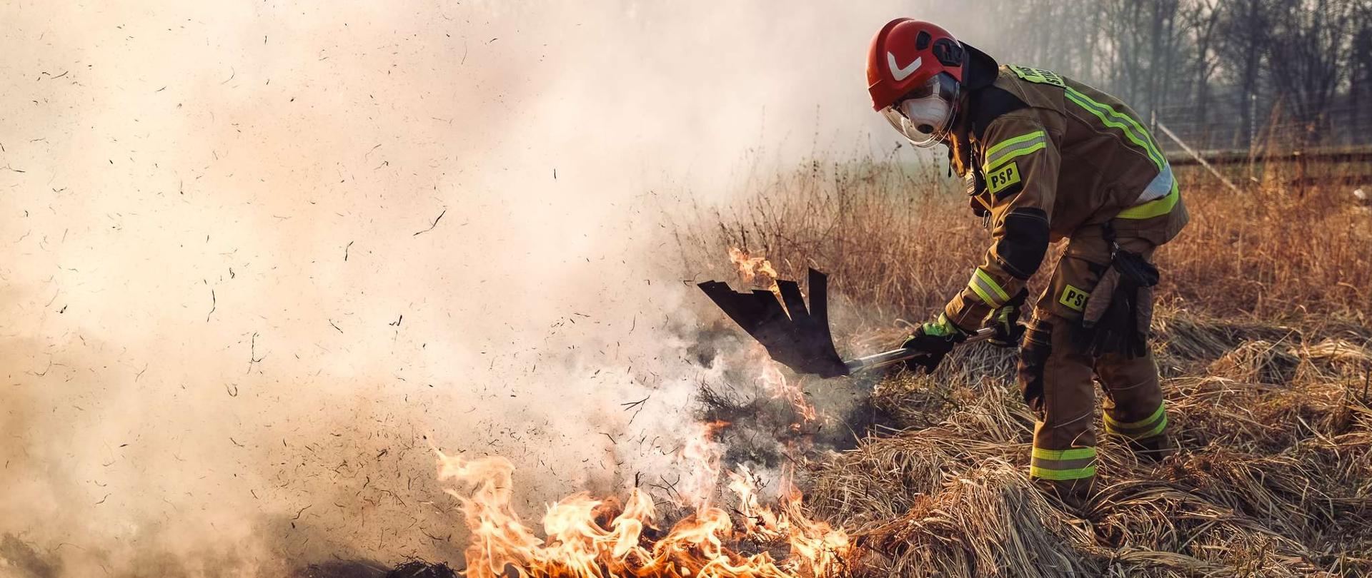 Zdjęcie przedstawia strażaka gaszącego pożar traw