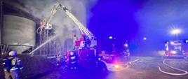 Zdjęcie przedstawia akcję gaśniczą, strażacy gasza pożar suszarni zbozowej prądami wody z podnosnika.