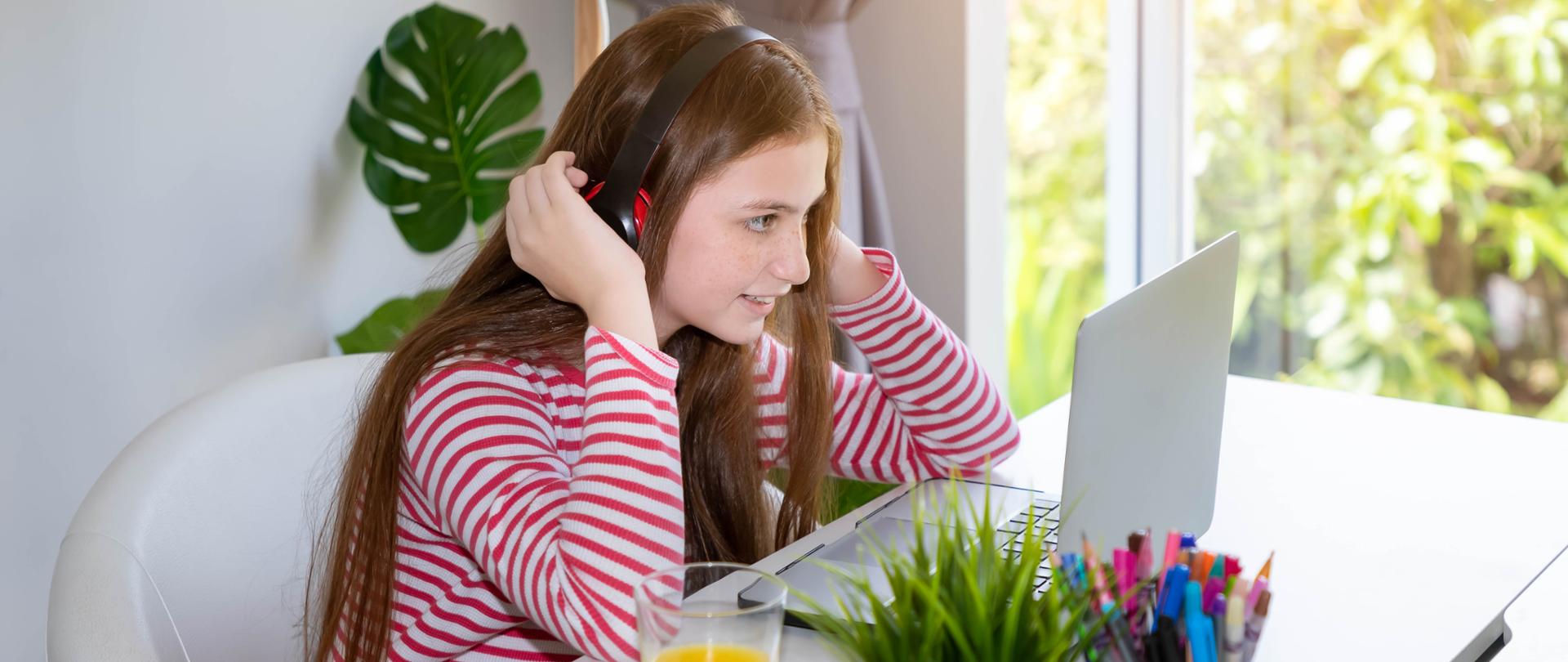 Girl using notebook computer laptop at home, with headphone