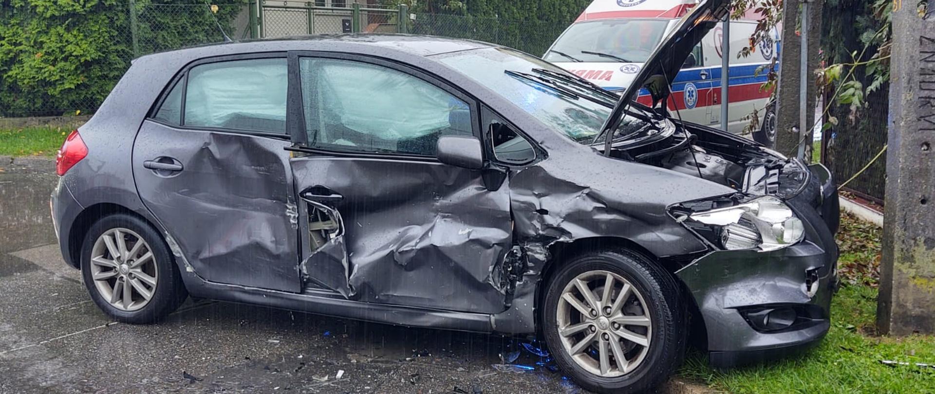 Widok prawej strony uszkodzonego samochodu przy słupie.