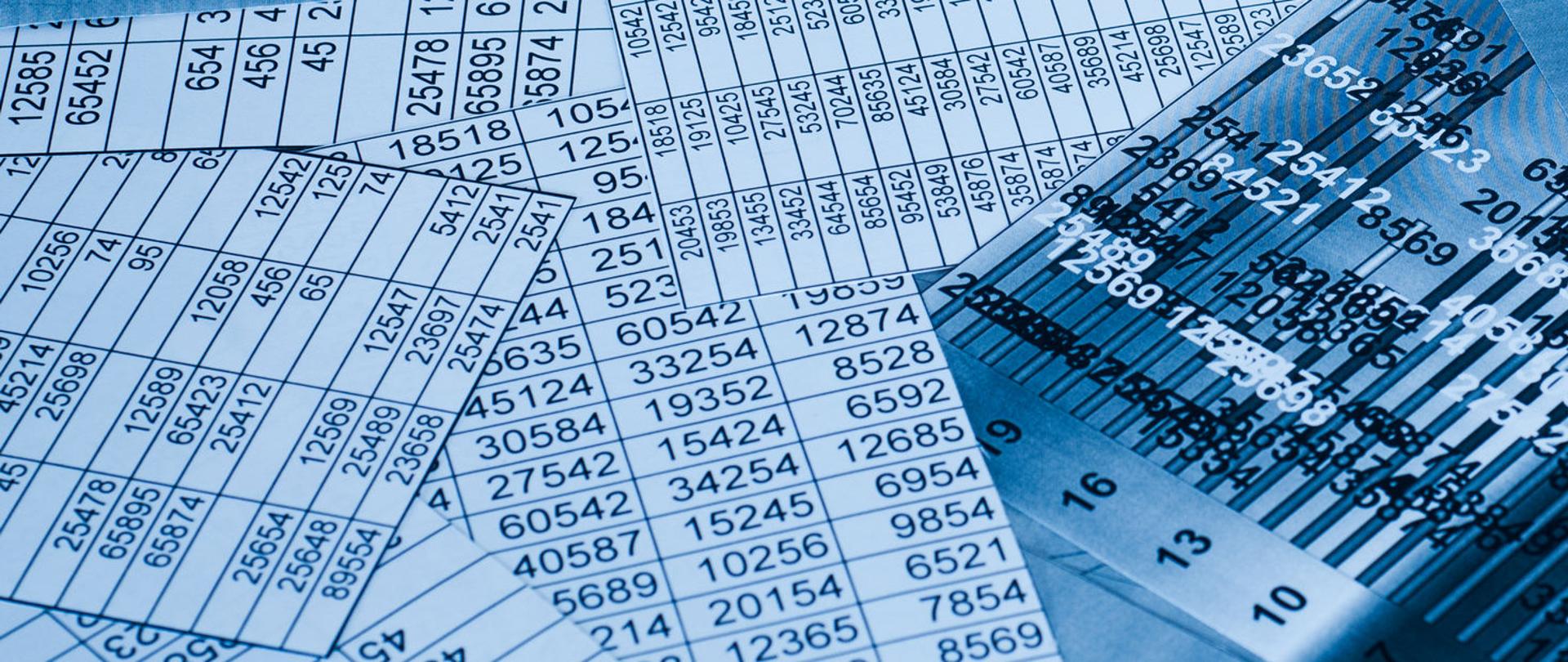 Porozrzucane wydruki, tabele z liczbami.