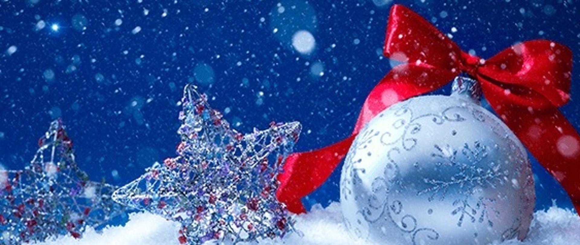 Zdjęcie przedstawia kartkę świąteczną w życzeniami, u góry bombka z czerwoną wstążką i dwiema gwiazdkami, na dole logo Państwowej Straży Pożarnej