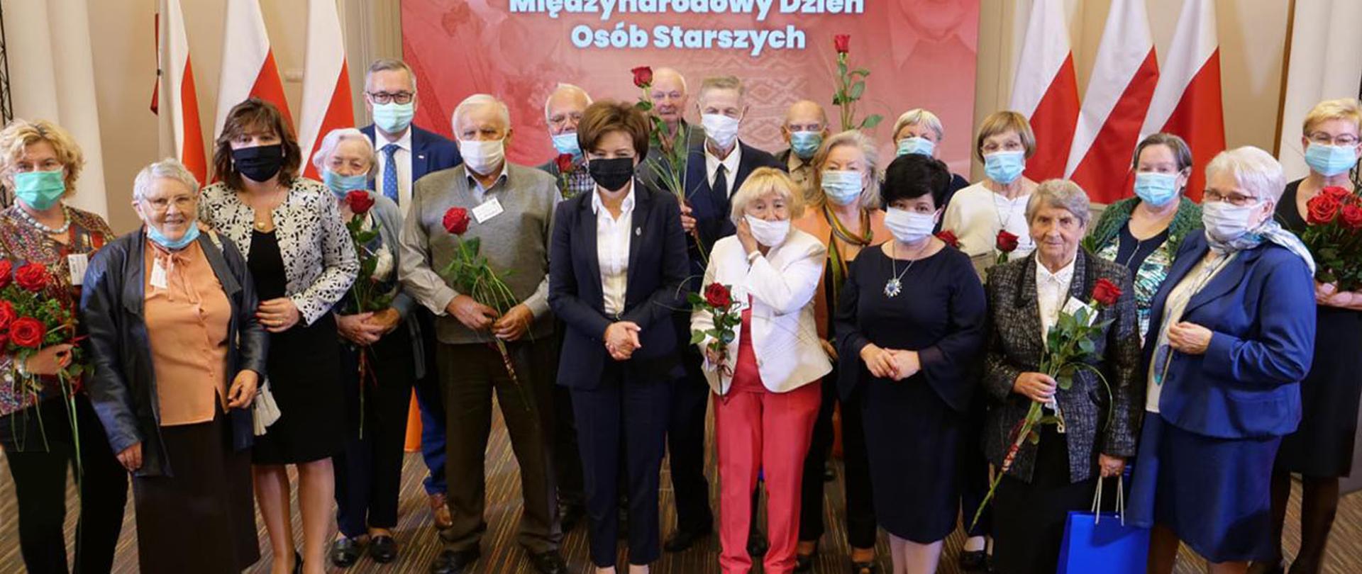 Zdjęcie pamiątkowe po spotkaniu. Minister Maląg w otoczeniu seniorów.