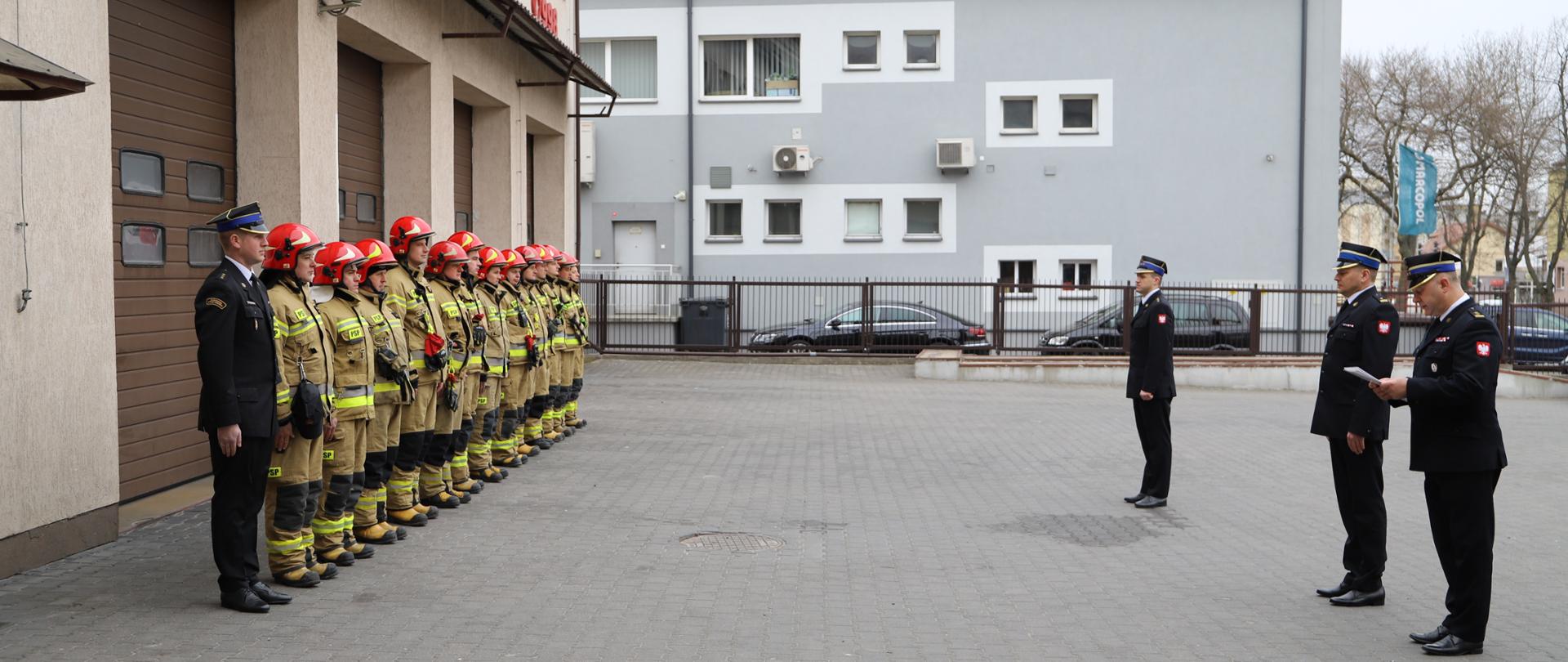 Zdjęcie przedstawia strażaków z Komendy Powiatowej Państwowej Straży Pożarnej w Zambrowie podczas uroczystego mianowania nowego Zastępcy Dowódcy Jednostki Ratowniczo-Gaśniczej w Zambrowie.