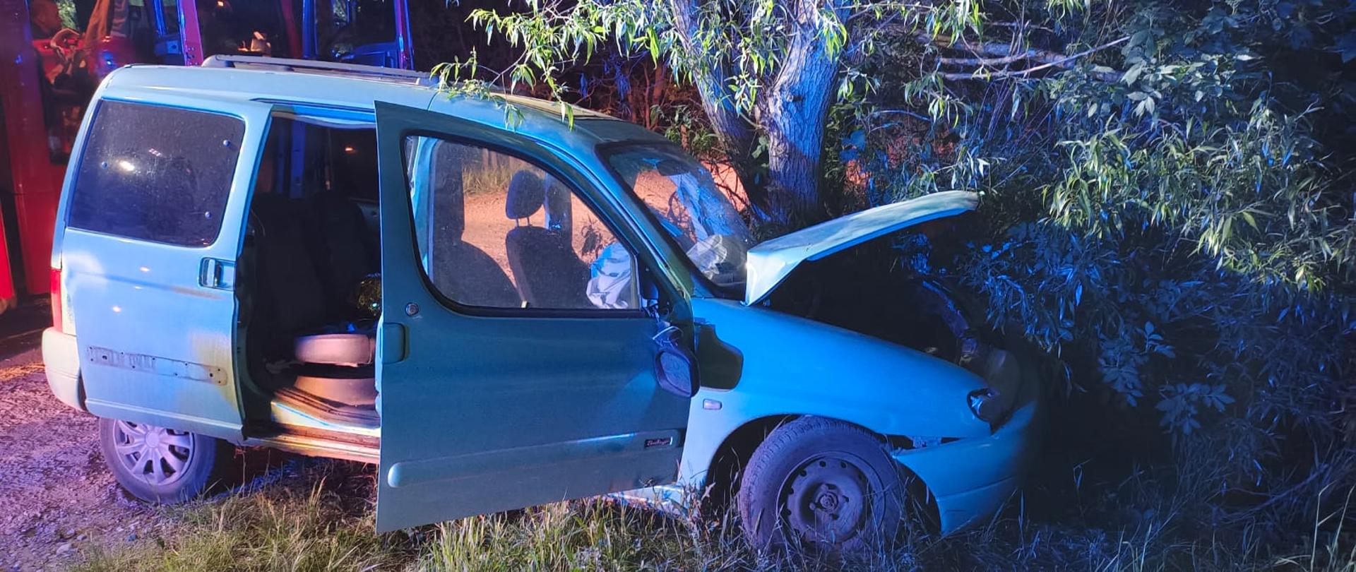 Widać uszkodzony przód samochodu, znajduje się blisko drzewa, od strony pasażera