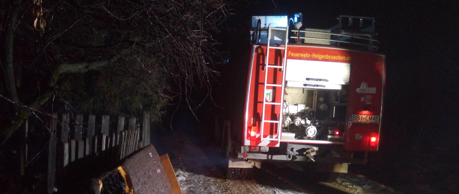 Samochód ratowniczo-gaśniczy biorący udział w akcji gaśniczej w Godziebach. Przy samochodzie, oparty o ogrodzenie nadpalony tapczan.