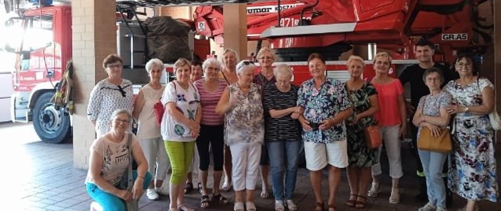 Grupa seniorów pozująca na tle samochodu pożarniczego