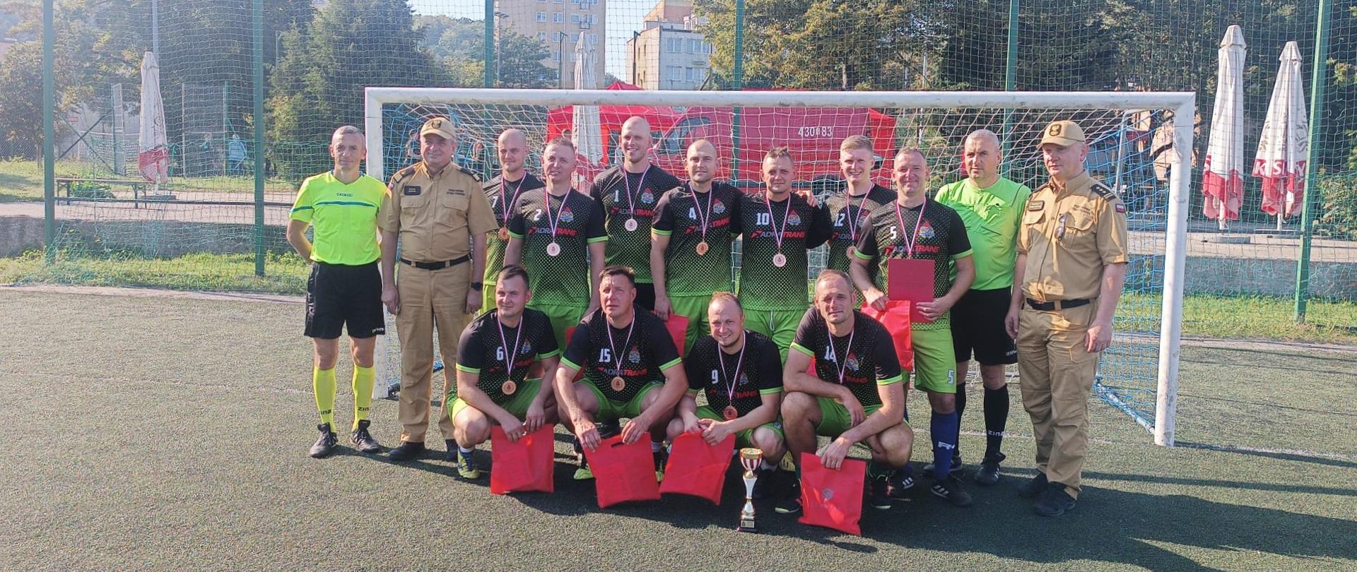 Drużyna KP PSP Kwidzyn pozuje do zdjęcia na boisku.