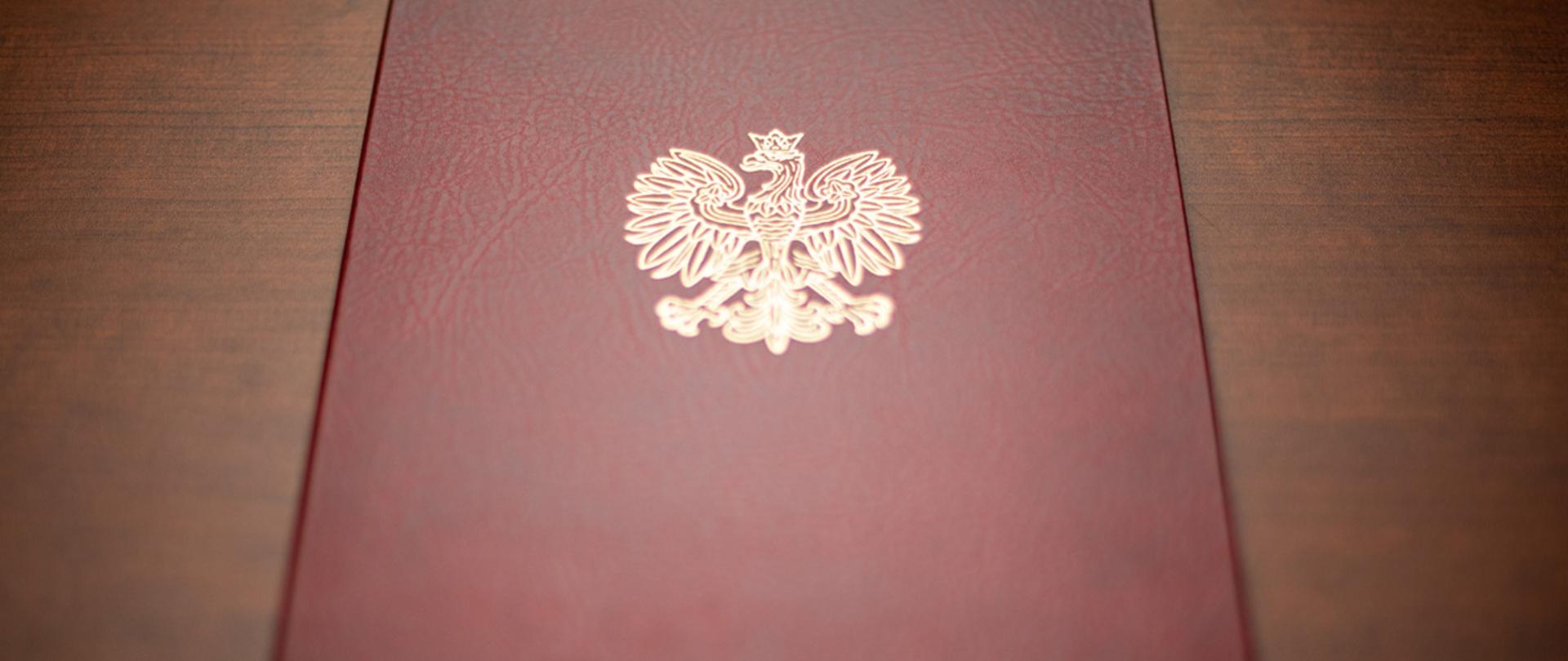 Na zdjęciu widać twardą oprawę na dokumenty z wytłoczonym orłem z godła narodowego.