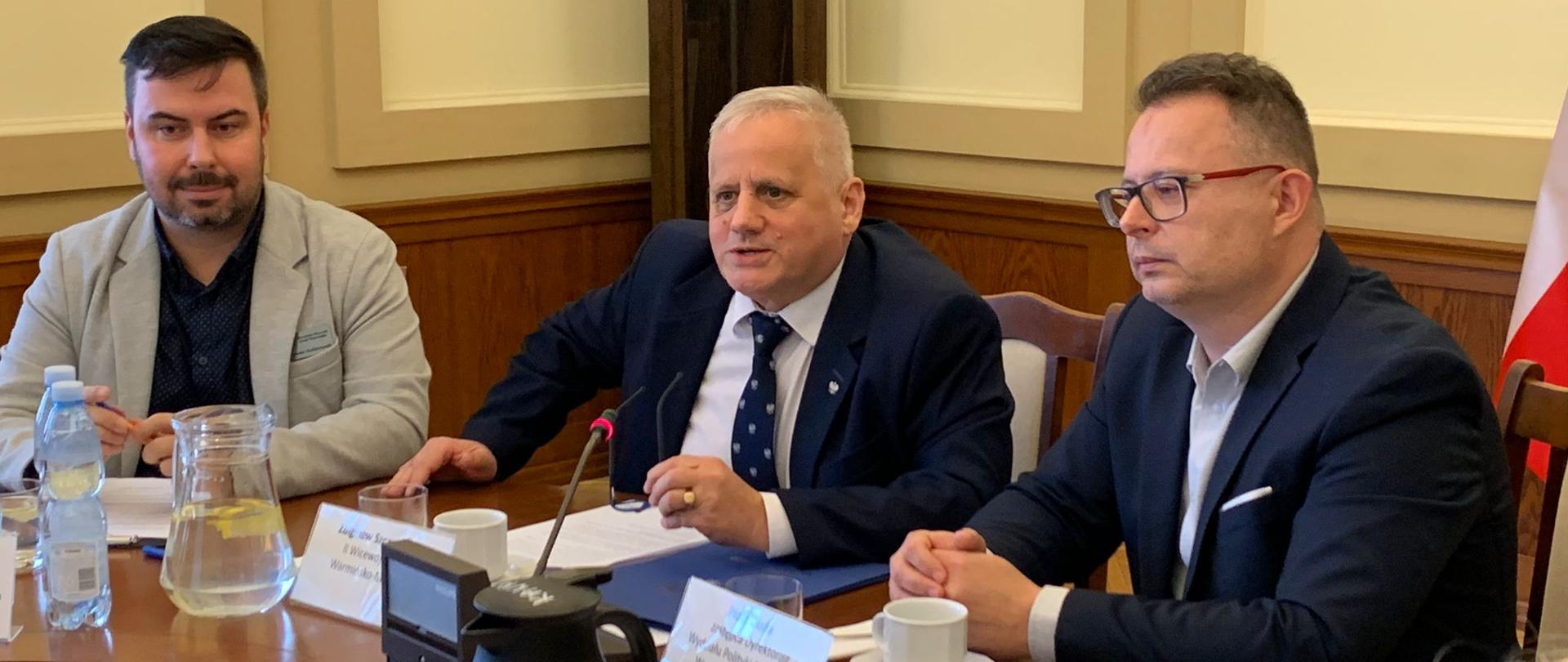 Trzech mężczyzn siedzi przy stole 