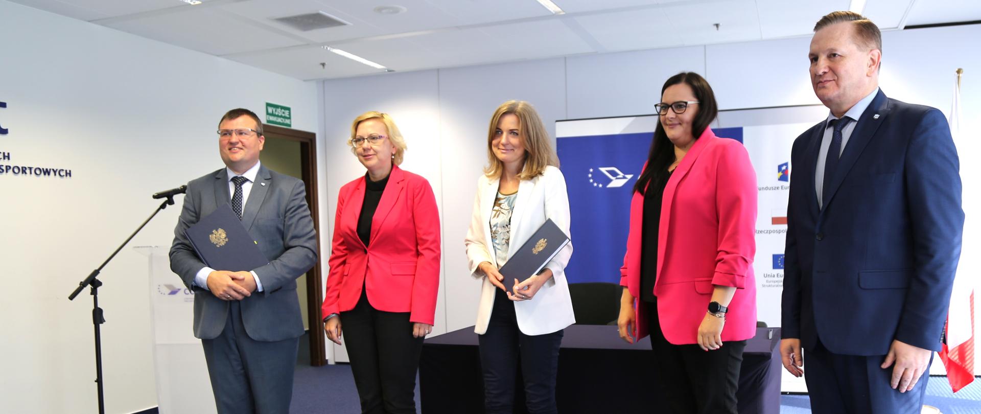 przed stolikiem na którym podpisano umowy stoją uczestnicy konferencji