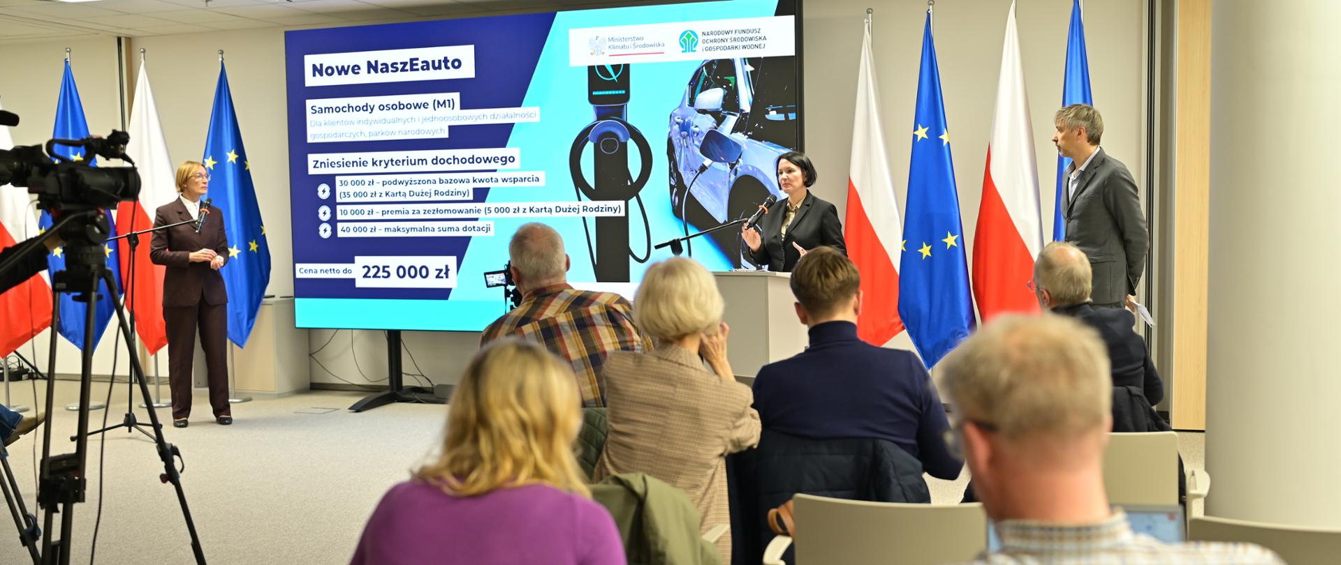 Na zdjęciu przy mównicy stoi prezes Dorota Zawadzka-Stępniak. Przemawia. Dziennikarze siedzą i słuchają.