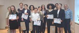 Uczestnicy konkursu stoją pozując do zdjęcia. Dzieci trzymają dyplomy i torby z upominkami.