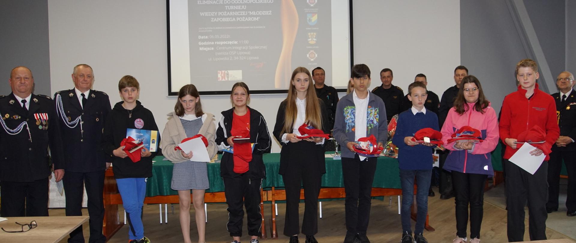 Zdjęcie przedstawia uczestników eliminacji powiatowych do Ogólnopolskiego Turnieju Wiedzy Pożarniczej siedzących w ustawionych w 2 szeregach ławkach podczas rozwiązywania testu. Zdjęcie wykonano w jednym z pomieszczeń Ochotniczej Straży Pożarnej w Lipowej. 