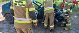 Strażacy rozcinają samochód osobowy za pomocą narzędzi hydraulicznych.