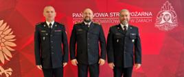 Na zdjęciu widoczny jest strażak otrzymujący nagrodę z Komendantem i Dowódcą JRG 