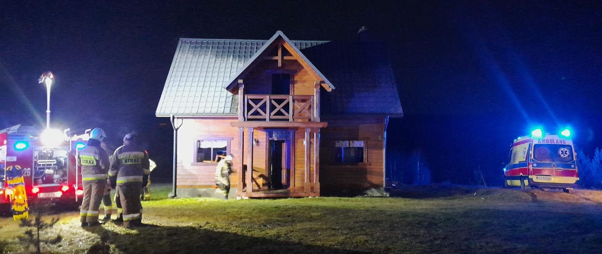 Domek letniskowy, w którym doszło do pożaru. W pobliżu pojazdy służb ratowniczych.