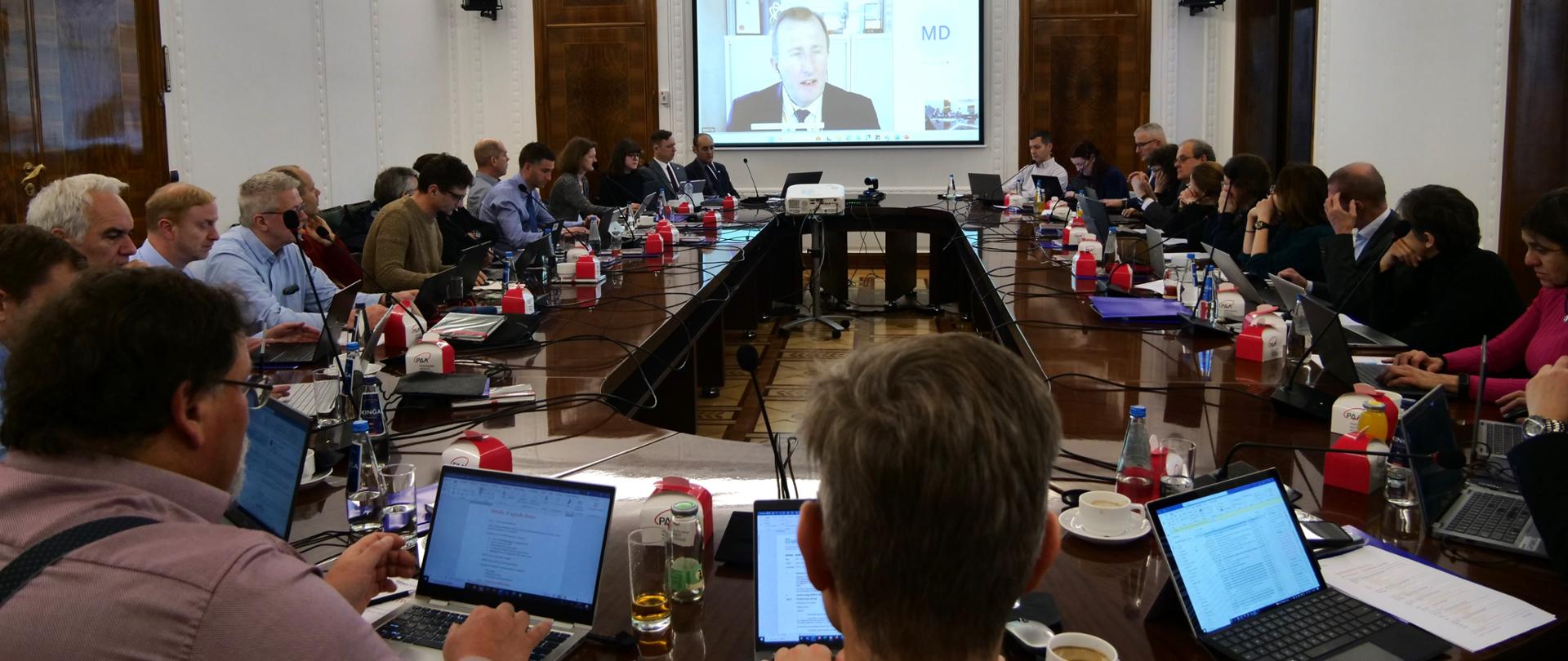 Posiedzenie WENRA RHWG (Reactor Harmonization Working Group) w siedzibie PAA: uczestnicy siedzą przy stole i słuchają wypowiedzi prelegenta