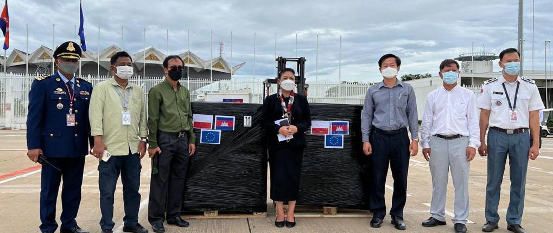 Siedem osób w maseczkach pozuje na tle palet. 