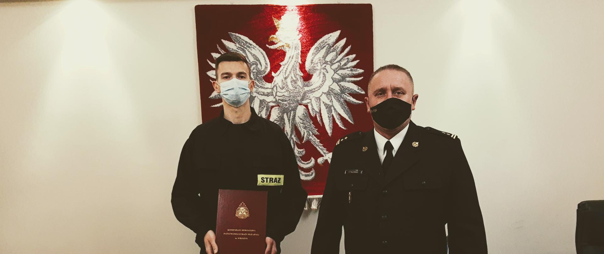 Dwóch strażaków na tle godła państwowego